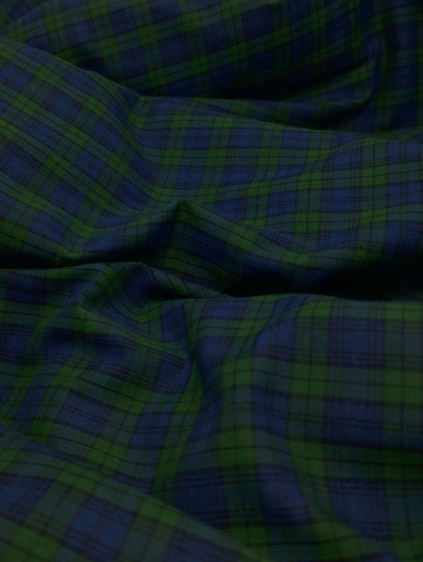 Close-up of green and blue checkered fabric with soft folds and texture