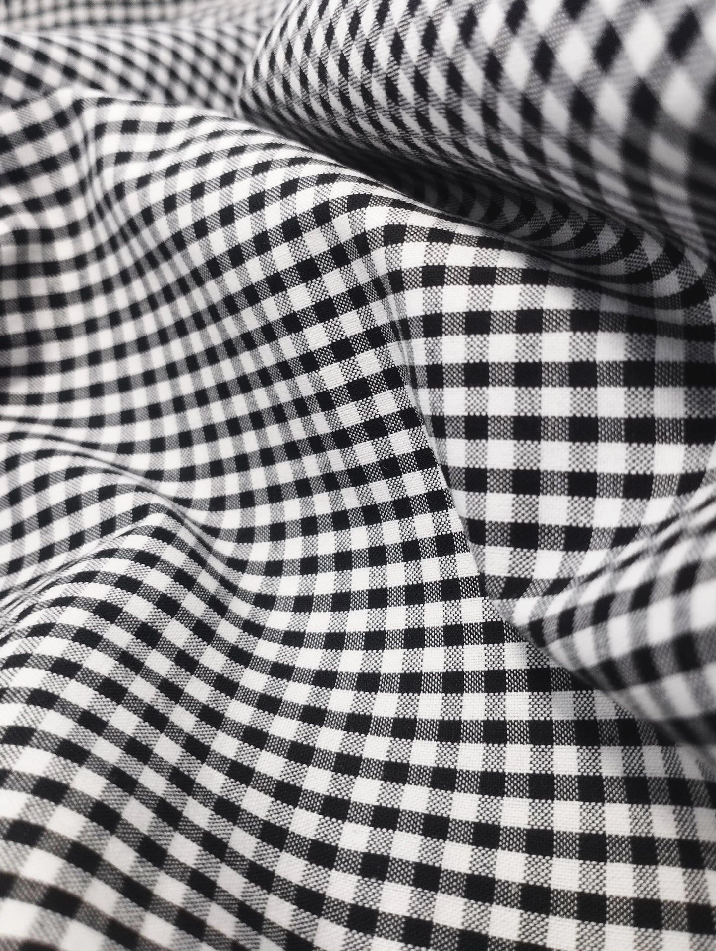 Close-up of black and white gingham check fabric with folds and textured weave