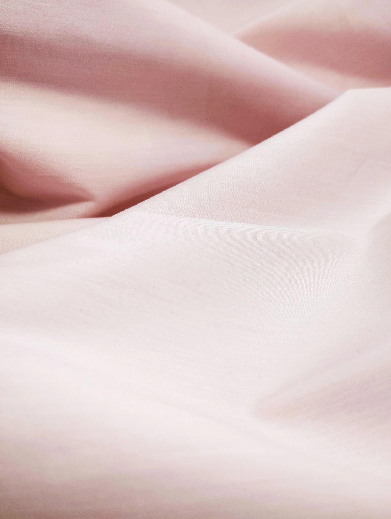 Close-up of stretchable light blush pink fabric with soft folds and smooth texture