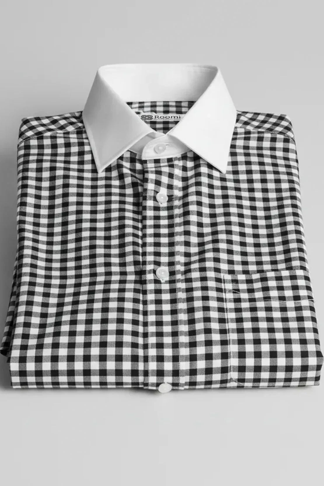 Folded black and white gingham check dress shirt with white collar and buttons on gray background