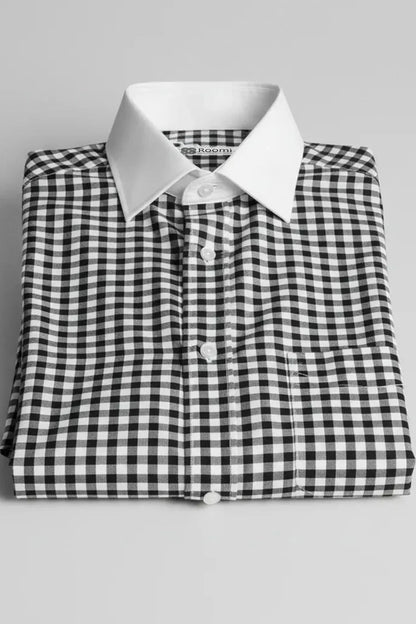 Folded black and white gingham check dress shirt with white collar and buttons on gray background