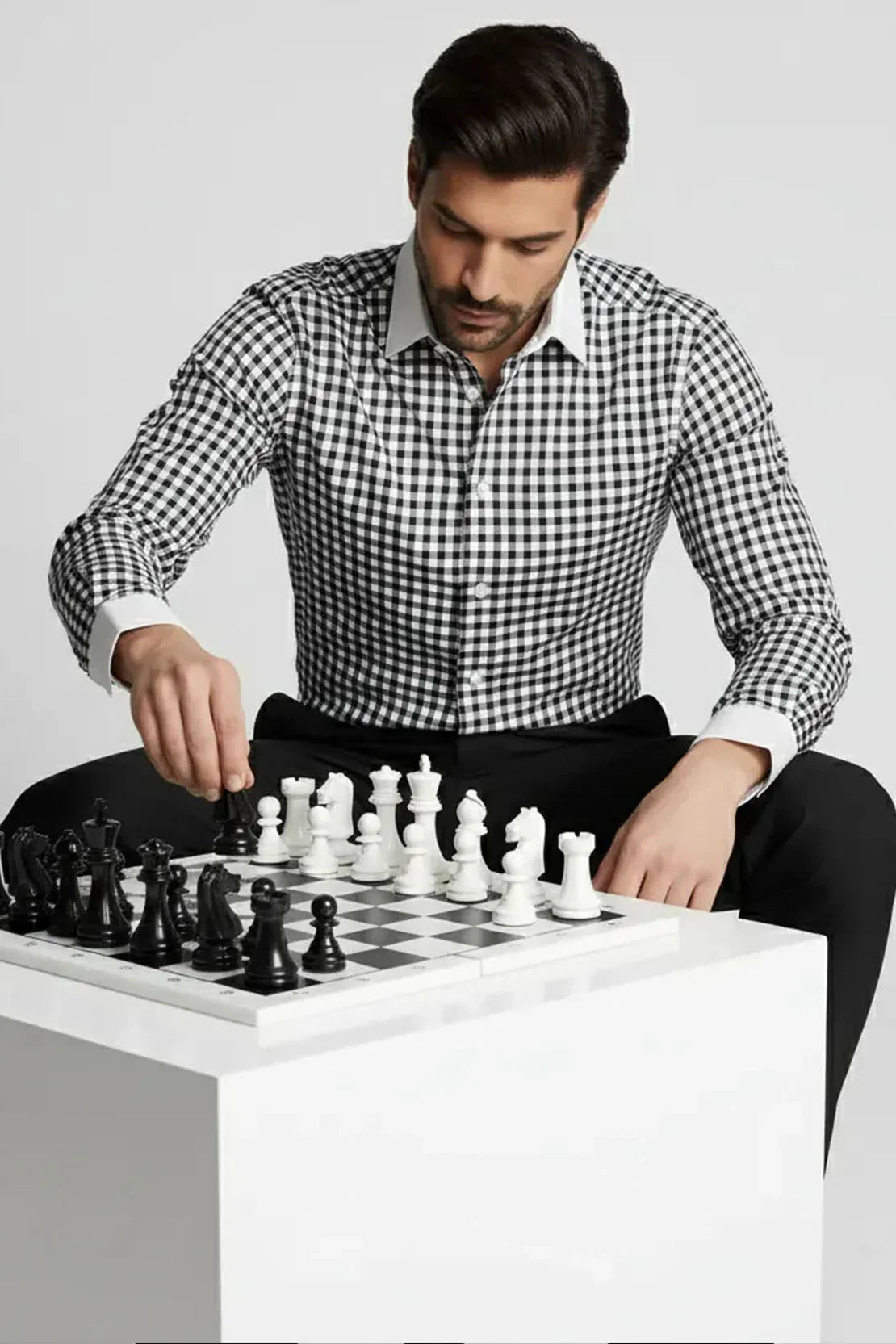 Man wearing black and white checkered shirt playing chess on black and white board