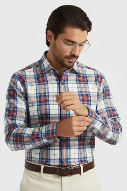 Man wearing blue and red plaid button-up shirt with beige pants and brown belt adjusting sleeve