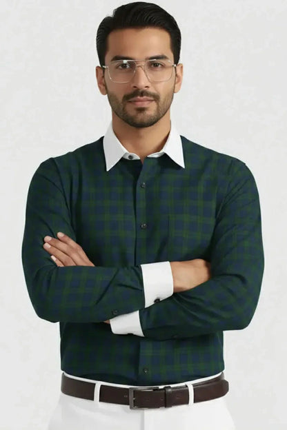 Man wearing green checkered shirt with white collar and cuffs, clear glasses, and brown belt