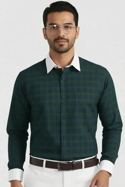 Man wearing green and navy checkered shirt with white collar and cuffs, paired with white pants and brown belt