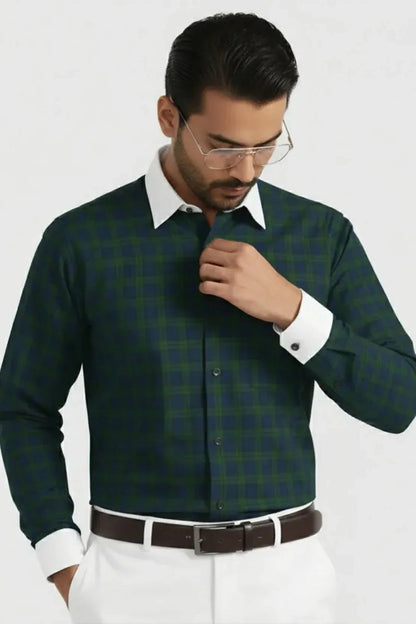 Man wearing green checked shirt with white collar and cuffs, white pants, and brown belt